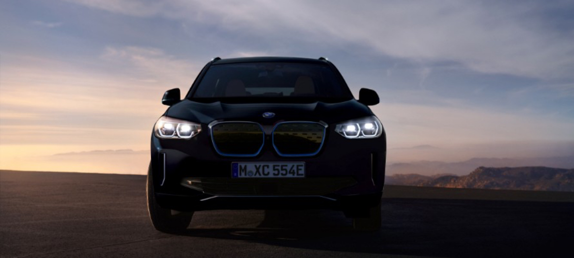 Lady standing next to white BMW iX3. Lady standing next to white BMW iX3.